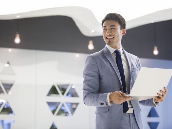 Young Chinese businessman working with laptop in office